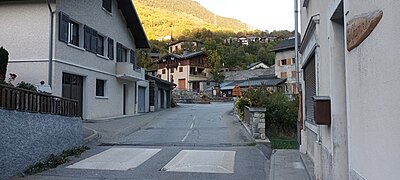 Rue principale du village de Francoz avec des maisons, des résidences et une route 215C.