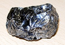 A lustrous blue gray potato shaped lump with an uneven and irregular corrugated surface.