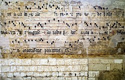 Notations musicales peinte sur un mur de pierre (en partie effacées).