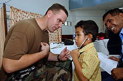 US Navy 050329-N-6665R-086 Lt. Cmdr. Jeffrey W. Bledsoe, a U.S. Navy nurse assigned to the Military Sealift Command (MSC) hospital ship USNS Mercy (T-AH 19), entertains a Dili child with his stethoscope