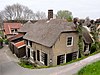 Hoeve, onder rieten wolfdak. Rechts een uitgebouwde opkamer met zadeldak en puntgevel