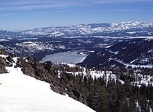 Large lake surrounded by snow-covered mountains, viewed from above.