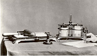 1875年にエジソンが考案したオートグラフィック印刷（米国特許第180857号）の用具一式。ローラーで原紙にインクを塗布して印刷を行う可動枠付き印刷台（写真左）が謄写器の原型となった。