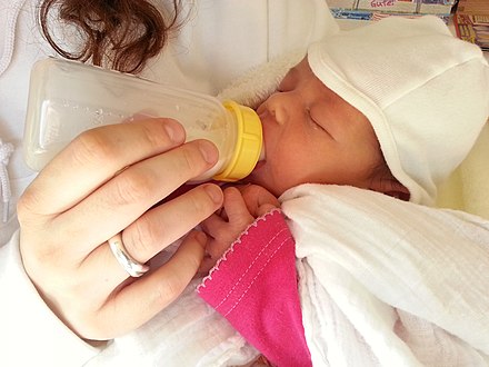 Newborn drinks milk from a baby bottle