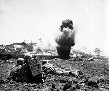 A 6th Division Marine demolition crew watches explosive charges detonate and destroy a Japanese cave, May 1945. OkinawaMarineCaveDemolition.jpg