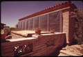 SIDE OF A HOME NEAR TUCSON, ARIZONA HAS BLACKENED PANELS UNDER THE PLASTIC SHEETING WHICH HEAT CIRCULATING AIR AND... - NARA - 555350.tif