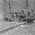 British troops firing a captured Hotchkiss M1914 machine gun during street fighting in Caen, 10 July 1944.