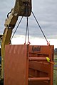 Trench safety - backhoe lowering trench box into trench (9247884221).jpg