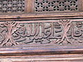 Détail d'une inscription arabe en style naskhi. Elle est sculptée en relief sur la traverse située au-dessous du tympan de la grande porte de la salle de prière.