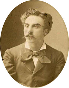 head and shoulders shot of a young man with medium length hair and a substantial moustache