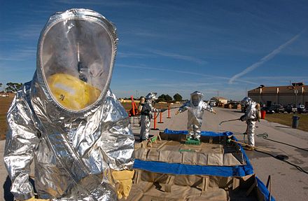 US Air Force firefighters in suits with an outer aluminized shell go through a decontamination line during an emergency management exercise.