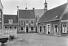 Pand, bestaande uit begane-grond met hoog zadeldak tussen puntgevels met vlechtingen. In de gepleisterde voorgevel een sieranker en een deuromlijsting met pilasters en hoofdgestel. Gevelsteen