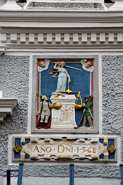 Justitia Relief an einem 1568 erbauten,1898 abgebrochenen Wohnhaus in der Auricher Innenstadt. Ein Bauer mit Springstock und ein Bewaffneter flankieren Justitia.