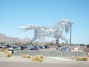 Eine überlebensgroße, metallene Pferdestatue, neben einem Parkplatz des Veranstaltungsgeländes.