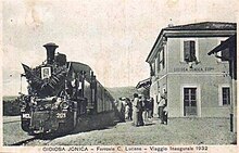 Cartolina postale raffigurante il treno inaugurale della linea Gioiosa Jonica-Mammola con in primo piano il frontale agghindato della locomotiva a vapore MCL 203. Il treno è in sosta a Gioiosa Jonica Superiore, stazione a due piani in stile MCL, tra la curiosità e lo stupore di grandi e piccoli presenti sulla banchina del primo binario.