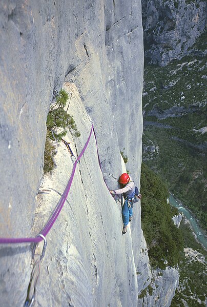 Climber following up the traverse section of Pichenibule 7b+ (5.12c) in the Verdon Gorge, one of the first-ever bolted sport climbing routes