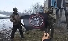 Wagner Group fighters pose after capturing the village of Mykolaivka, north of Soledar, 2 February 2023 Wagner flag.jpg