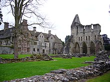 Wir sehen ein Foto von Wenlock Abbey.  Rechts das noch stehende Kloster.  Links die Ruinen der alten Abtei