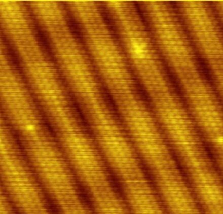 Scanning tunneling microscope image showing the individual atoms making up this gold (100) surface. The surface atoms deviate from the bulk crystal structure and arrange in columns several atoms wide with pits between them (See surface reconstruction).