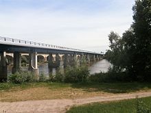 Geniş bir nehri geçen bir karayolu köprüsünün renkli fotoğrafı.