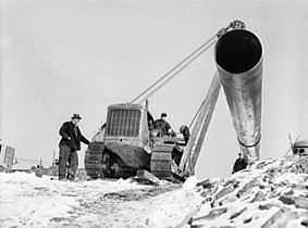 Hoisting pipe into place with a caterpillar tractor,