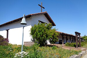 Un bâtiment blanc avec un toit sombre et une croix simple debout sur le toit