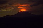 Nattetid lyser den glödande lavasjön i Nyiragongos krater upp molnen ovanför vulkanen.
