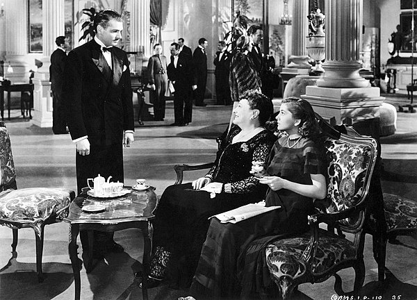 In Monte Carlo, Max de Winter (Laurence Olivier) stops to speak to Mrs. Edythe Van Hopper (Florence Bates) only after recognizing her companion (Joan 