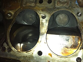 Closeup of two cylinders in a 3-litre Rover IOE Engine. You can see the combustion chamber, angled piston top, and exhaust valve. Rover 3-Litre Combustion Chamber.JPG