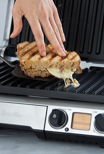 A sandwich being lifted off a panini grill with a spatula