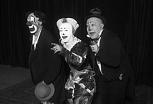 Photographie en noir et blanc de trois hommes aux visages peints.