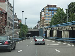 Entrée du tunnel de la Paix sous le boulevard Pierre Mayence. À gauche, la rue d'Assaut. À droite en bas, entrée depuis la route de Philippeville, en haut, sortie vers la Ville-Basse.