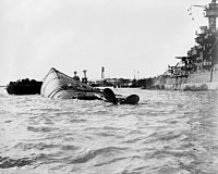 横転沈没した「オクラホマ」。背後の戦艦は「メリーランド」。