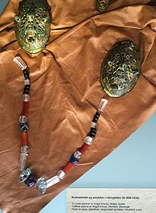 Женский убор: парные скорлуповидные фибулы и нитка бус из цветного стекла, сердолика и горного хрусталя, Археологический музей в Ставангере, Норвегия