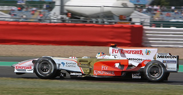 a white and gold Formula One car drives around a course