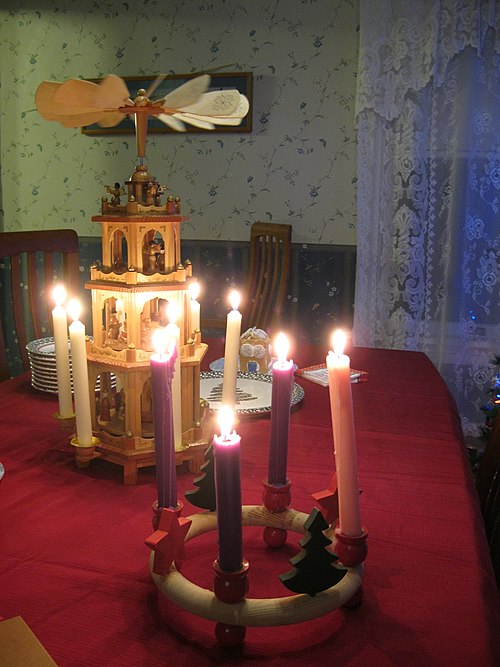 An Advent wreath and Christmas pyramid adorn a dining table.