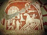 A Valkyrie, drinking horn in hands, awaits at the gates of Valhalla on the Tjängvide image stone from Gotland, housed at the Swedish Museum of National Antiquities in Stockholm, Sweden.