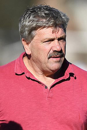 A grey-haired man with a moustache in a red shirt