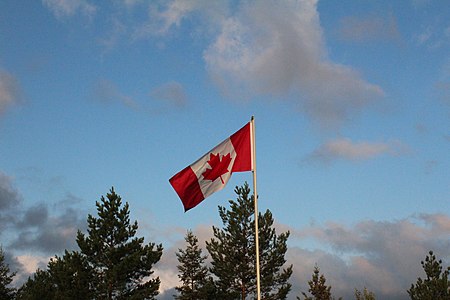 A Canadian flag waves in the wind just after sunrise
