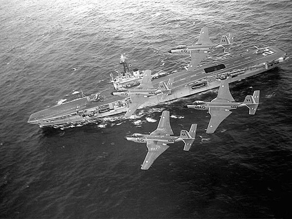 Four F2H-3 Banshee fly overhead HMCS Bonaventure. Bonaventure was the last aircraft carrier in service with the RCN.