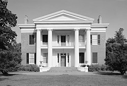 Two-story building fronted with a portico with four Greek columns