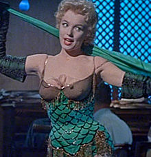 Monroe in Bus Stop. She is wearing a green stage costume with gold trimmings while singing.