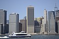 A NYC Ferry boat along the Manhattan skyline, seen from Brooklyn Bridge Park, New York City.