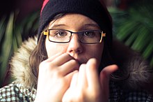 A young woman bites her fingernails.