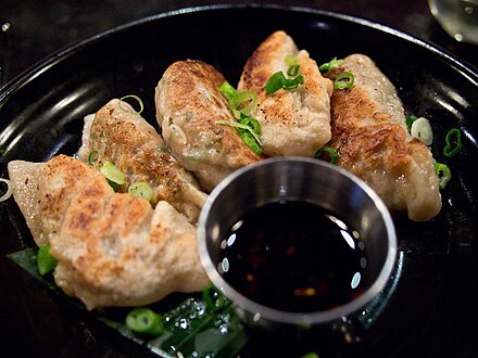 Fried dumplings served with green onion and sauce