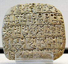 Comprimido aproximadamente cuadrado marcado con signos cuneiformes.