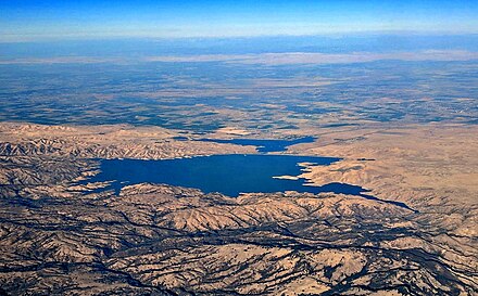 The San Luis Reservoir and O'Neill Forebay, aerial view from near Hollister, California, with late afternoon shadows outlining the hills of the oak woodlands around it.