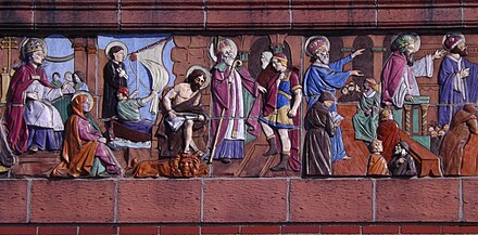 A close-up of part of the decorated frieze above the arcaded entrance of St. Luke's: a painted terra-cotta relief sculpture of scenes from the New Testament.