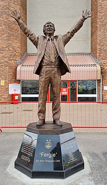 statue of football manager in suit with hand held aloft in celebration