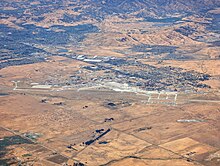 An aerial view of a military air base bordering on arid farmland.